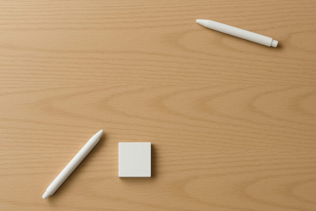 文具が手前と奥に分かれて置かれ、前後の距離がそろっていないデスク俯瞰シーン。
