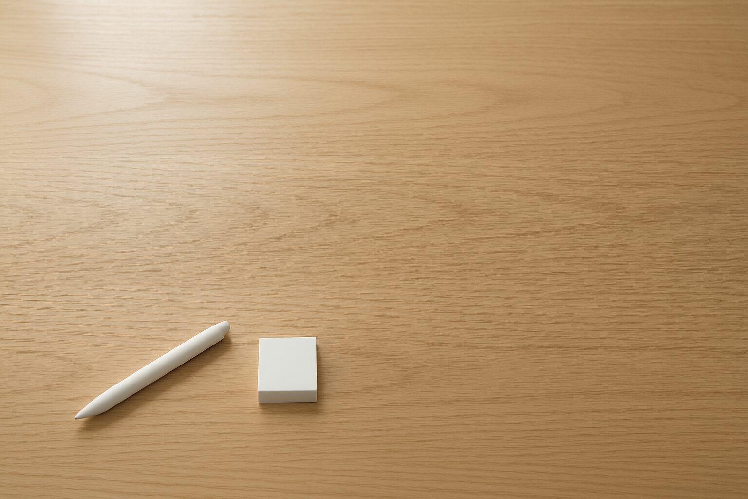 木目デスクを俯瞰した静かな作業シーン。手前に文具がそろい、奥に余白がある様子。